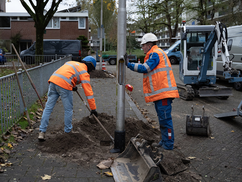 men in orange vests working on a pole