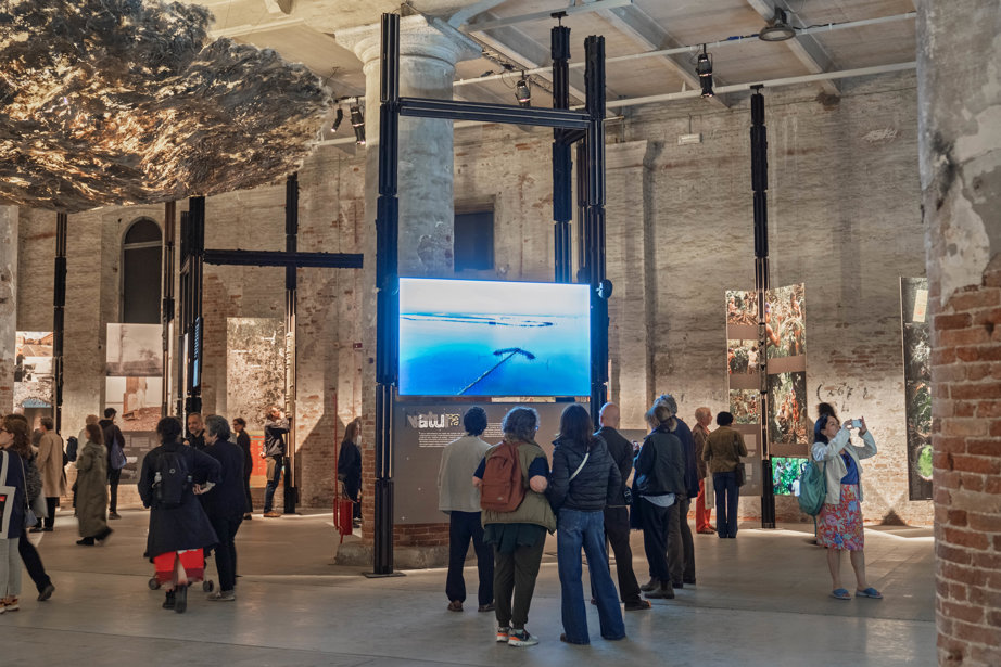 a group of people standing in a large building with a large screen