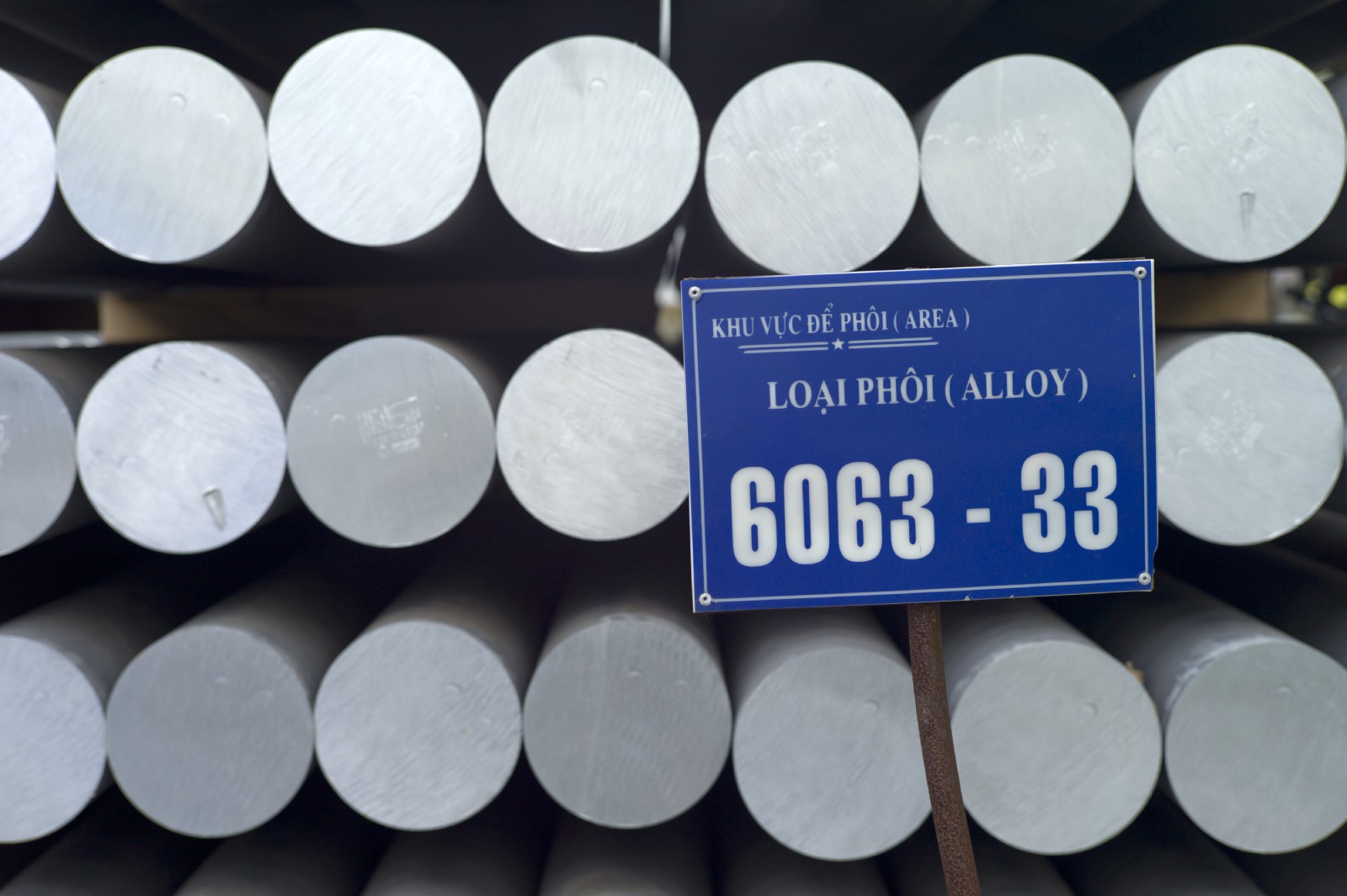 Stacks of aluminium rods, with a vietnamese sign.